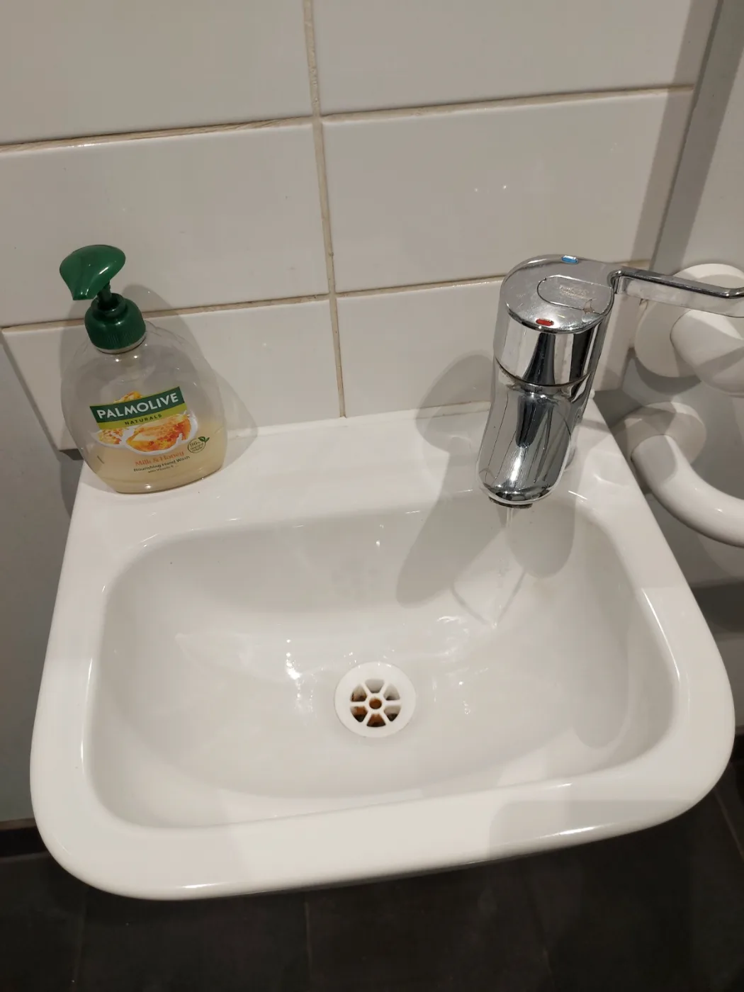 Small bathroom sink, faucet and tiles cleaned and shining